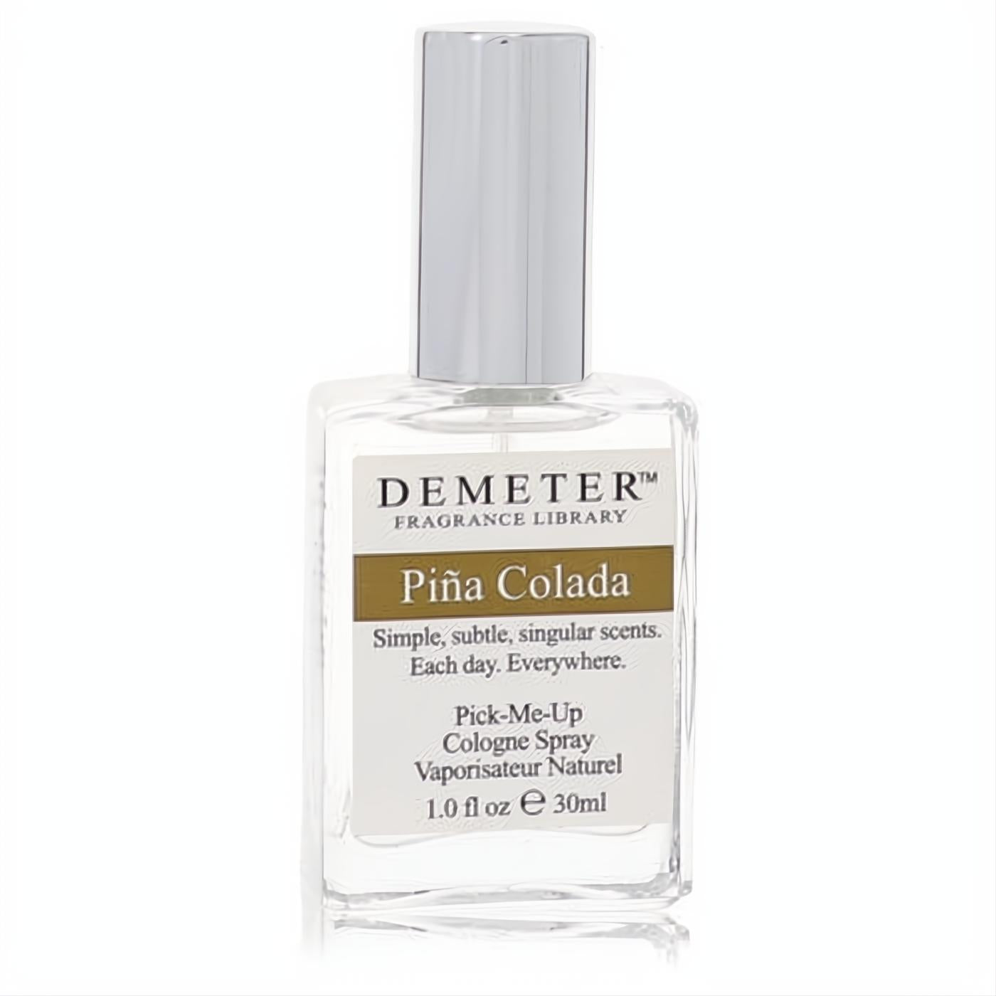 Demeter Pina Colada 1 oz cologne spray. Clear glass bottle, sleek silver cap, and a white label with a prominent brown 'Pina Colada' band.