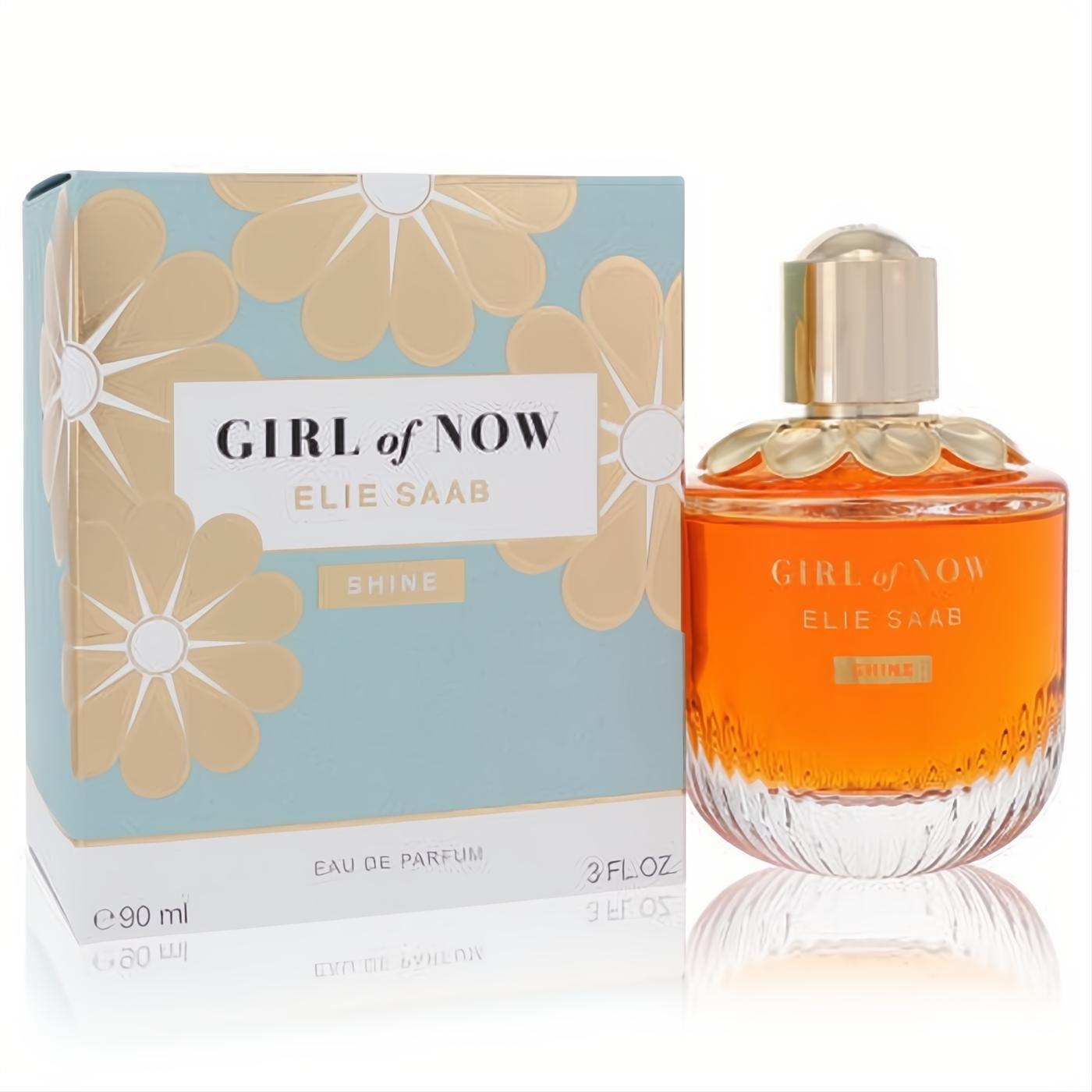 Elie Saab Girl of Now Shine 3 oz Eau De Parfum. Radiant orange liquid in a clear bottle with a gold floral cap, next to its elegant blue and gold box.