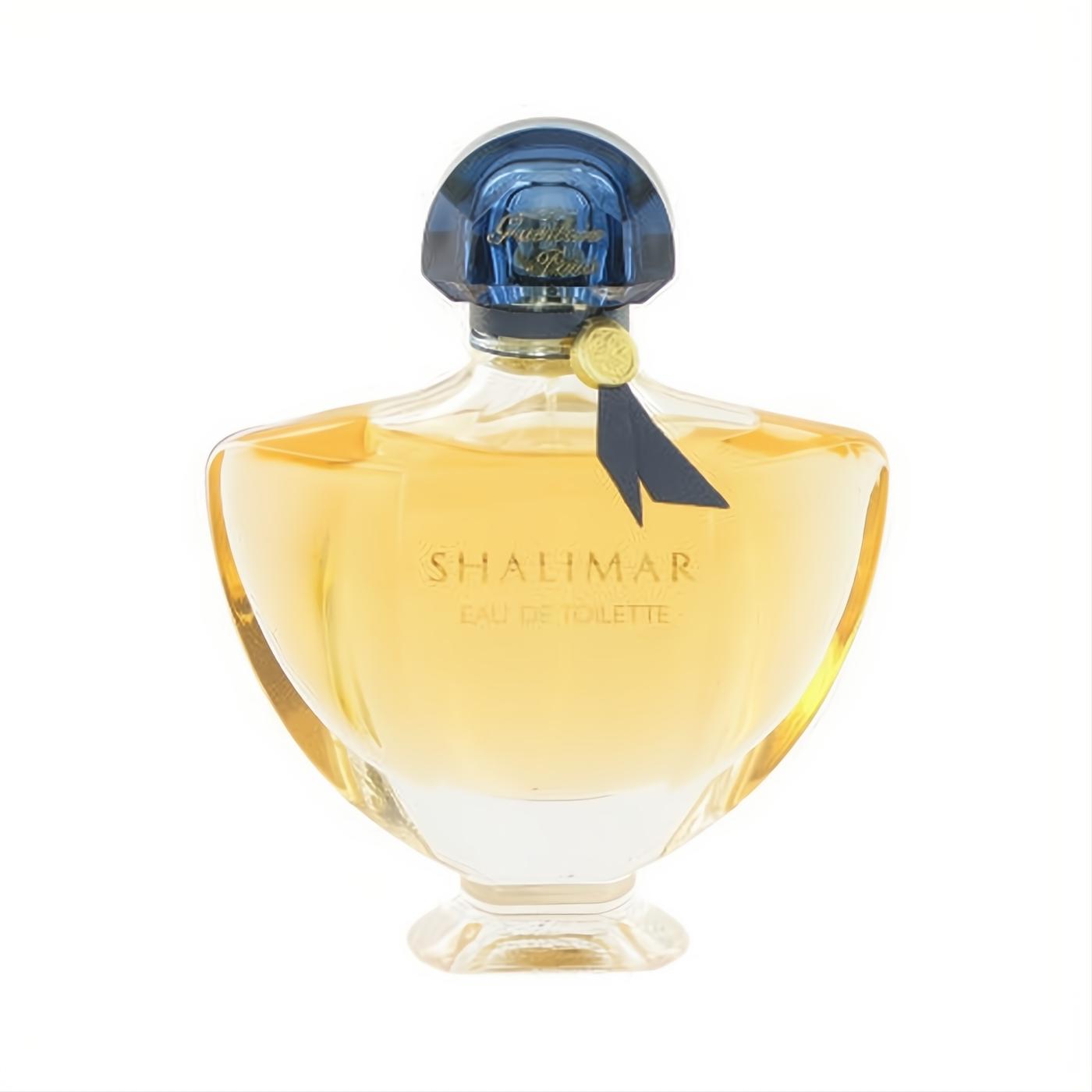 Captivating Guerlain Shalimar Eau de Toilette 3 oz. Golden liquid in a sculpted glass bottle with a deep blue cap and ribbon.