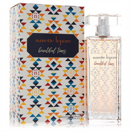 Nanette Lepore Beautiful Times 3.4 oz EDP. Elegant clear glass bottle with amber perfume, beside its vibrant orange, blue, red geometric box.