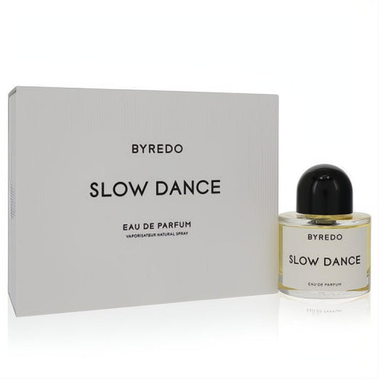Sophisticated Byredo Slow Dance 1.6 oz unisex Eau De Parfum. Clear bottle with black cap and golden liquid, next to its sleek white box.