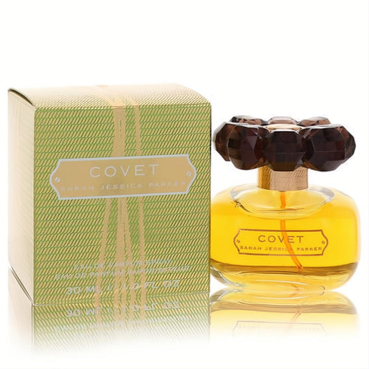 Covet by SJP 1 oz Eau De Parfum: a radiant clear bottle with golden liquid and a striking dark brown jewel-like cap, next to its elegant green box.