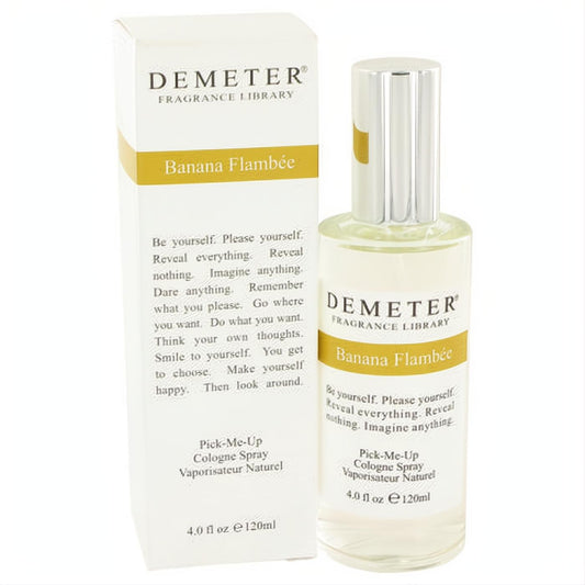 Demeter Banana Flambee 4 oz cologne spray. Clear glass bottle, sleek silver cap, and elegant white box with yellow branding.