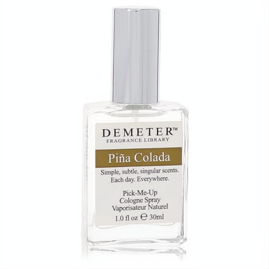 Demeter Pina Colada 1 oz cologne spray. Clear glass bottle, sleek silver cap, and a white label with a prominent brown 'Pina Colada' band.