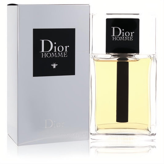 Experience Dior Homme men's Eau De Toilette. Sleek clear glass bottle with black cap and golden liquid, beside its elegant silver box.