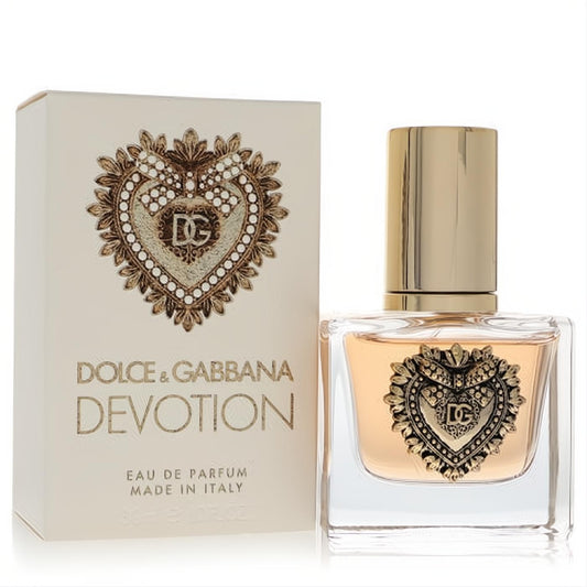 Luxurious Dolce & Gabbana Devotion 1 oz EDP spray. Clear bottle features iconic gold Sacred Heart design, beside its cream box.