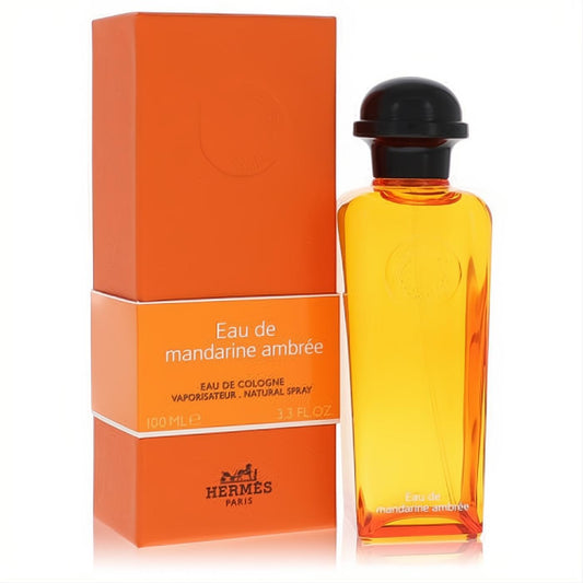 Hermes Eau De Mandarine Ambree 3.3 oz unisex cologne in a radiant amber bottle with black cap, next to its iconic orange box.