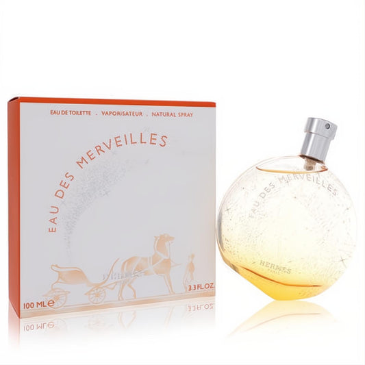 Hermes Eau Des Merveilles 3.3 fl oz EDT. Luxurious spherical glass bottle with amber liquid and silver cap, next to its iconic orange box.