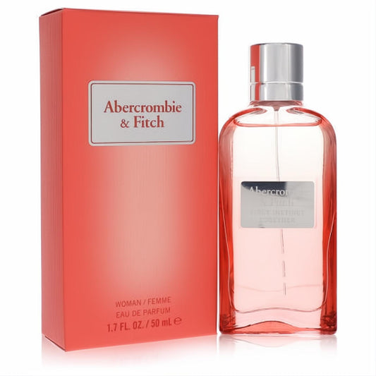 Abercrombie & Fitch First Instinct Together 1.7 oz EDP. Chic clear bottle with pink fragrance, silver cap, beside its vibrant coral box.