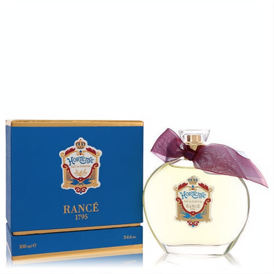 Rance Hortense 3.4 oz Eau De Parfum: elegant clear bottle with gold cap, burgundy ribbon, and ornate label, next to royal blue box.