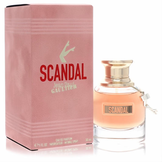 Experience Scandal! Jean Paul Gaultier 1 oz EDP spray: elegant pink box, clear bottle with peachy liquid, gold cap, and signature leg charm.