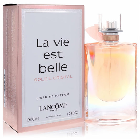 Lancome La Vie Est Belle Soleil Cristal 1.7 oz EDP. Radiant amber perfume bottle with a delicate rose gold bow, beside its elegant pink box.