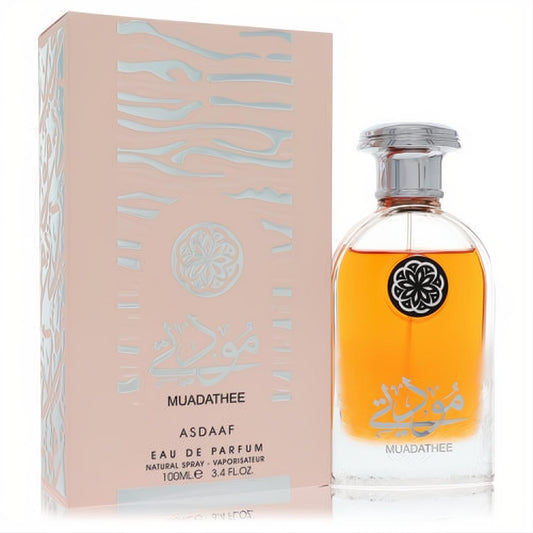Experience Lattafa Asdaaf Muadathee unisex EDP, 3.4 oz. Amber liquid in a clear bottle with silver cap, and a peach box with elegant silver design.