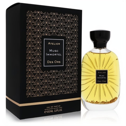 Luxurious Atelier Des Ors Musc Immortel 3.3 oz EDP spray. Clear bottle with shimmering gold flakes, next to its elegant black art deco box.
