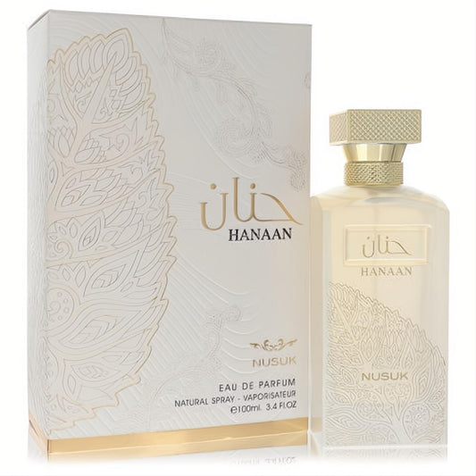 Exquisite Nusuk Hanaan 3.4 oz EDP spray. Clear bottle with gold cap, beside its elegant white and gold patterned box.