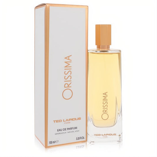 Ted Lapidus Orissima 3.3 oz women's Eau De Parfum. Sleek clear bottle with golden liquid and cap, next to its elegant white and gold box.