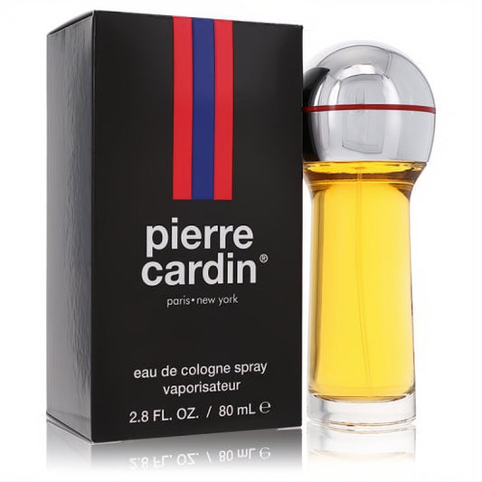 Pierre Cardin men's 2.8 oz cologne: golden liquid in a clear bottle with a unique silver cap, beside its sleek black box with signature stripes.