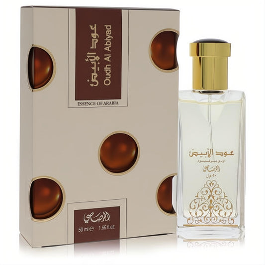 Rasasi Oudh Al Abiyad 1.7 oz unisex EDP. Clear glass bottle with luxurious gold cap, ornate design, beside its elegant beige box.