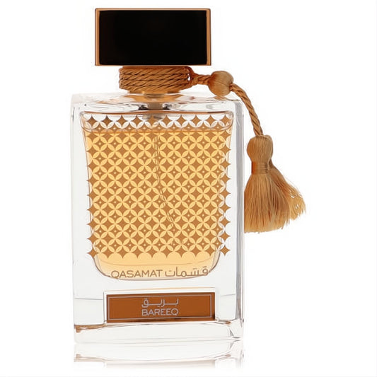 Luxurious Rasasi Qasamat Bareeq 2.2 oz unisex EDP. Clear bottle with golden liquid, intricate gold geometric pattern, black cap, and decorative gold tassel.
