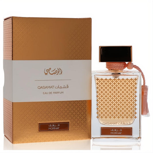 Rasasi Qasamat Morhaf unisex EDP: clear bottle with gold liquid, intricate pattern, peach tassel, and elegant gold box.