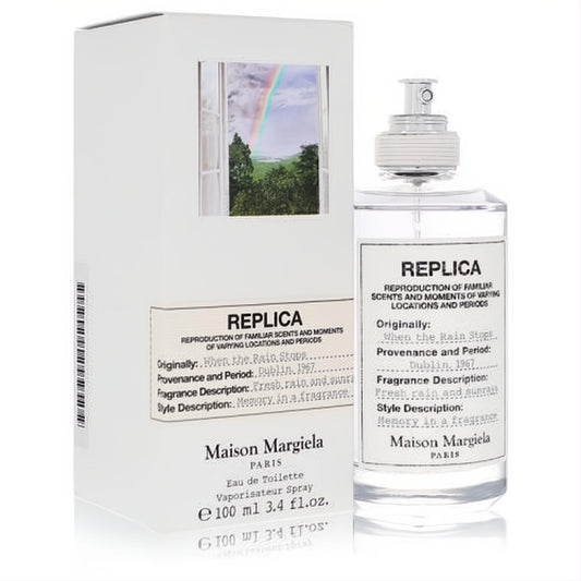 Maison Margiela Replica When The Rain Stops 3.4 oz EDT. Clear glass bottle, sleek white label, beside its iconic box with a vibrant rainbow.
