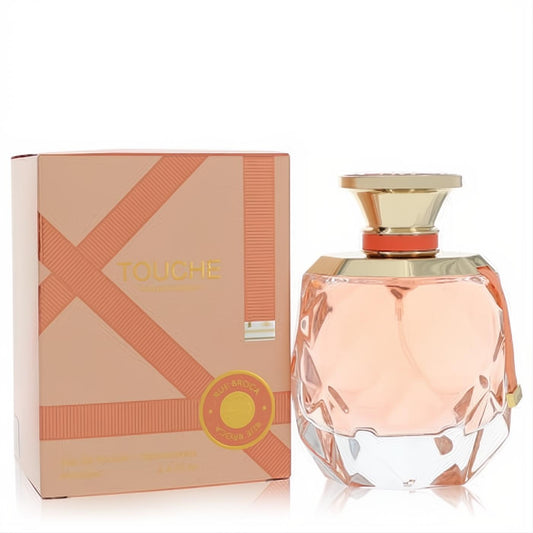 Rue Broca Touche Eau De Parfum: a luxurious faceted peach glass bottle with gold cap, next to its elegant ribbon-design box.