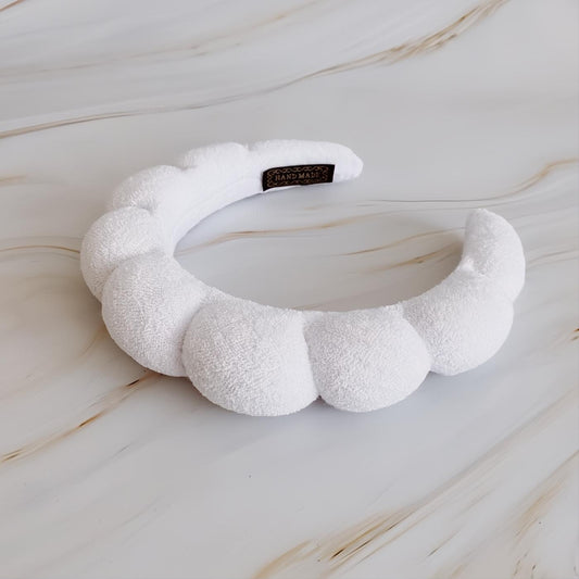Soft white terry cloth headband with a playful puffy scalloped design and "HAND MADE" tag. Perfect for comfort and style.