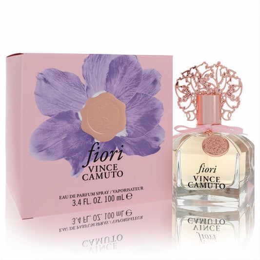Elegant Vince Camuto Fiori 3.4 oz EDP. Features a clear faceted bottle, ornate rose gold cap, and a beautiful pink box with a purple flower.