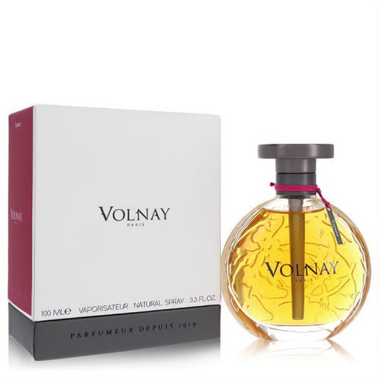 Luxurious Volnay Yapana 3.4 oz EDP. Round clear glass bottle with amber liquid, floral design, dark cap, pink ribbon, and elegant white box.